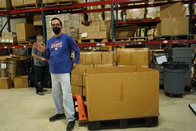 CVR participant standing beside a large cardboard bin in the warehouse.