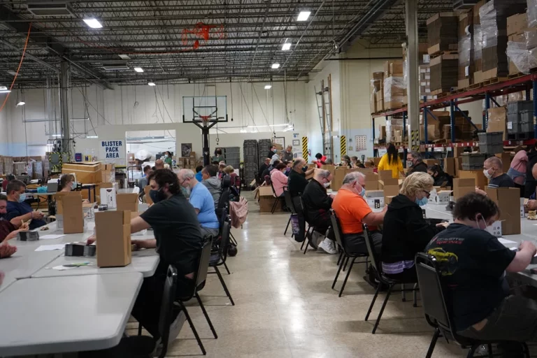 CVR participants working at long tables in the Production Center warehouse.