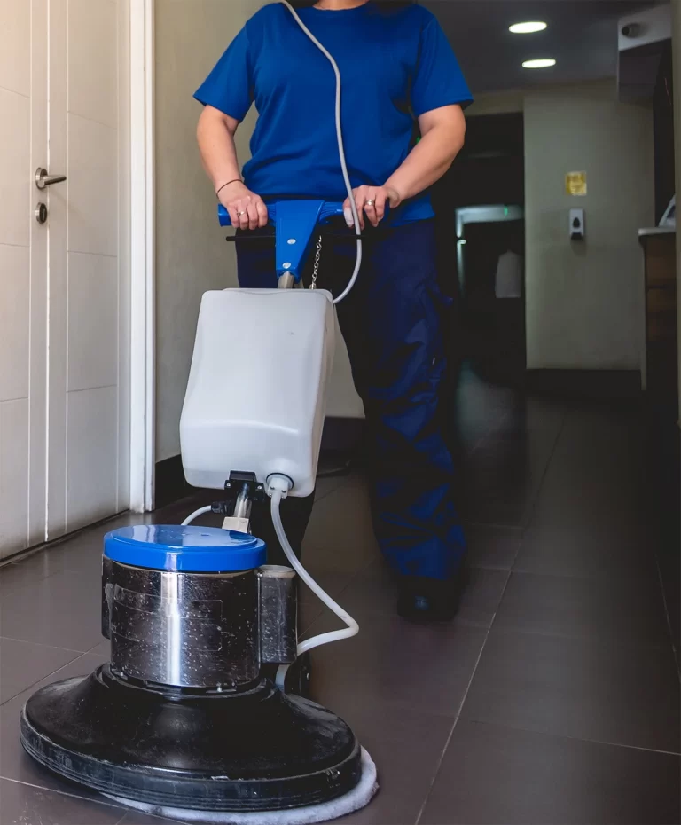 Individual operating a floor cleaning machine as part of custodial training.