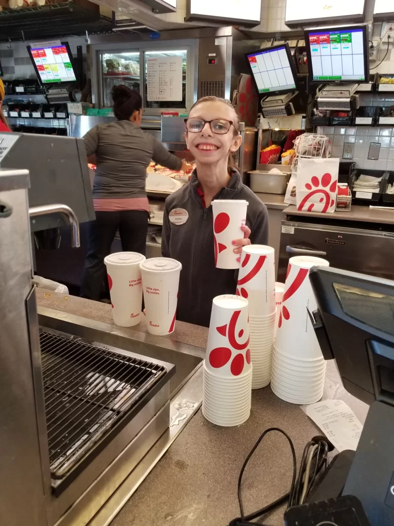 CVR participant smiling while preparing drinks behind the counter at a fast food chain.